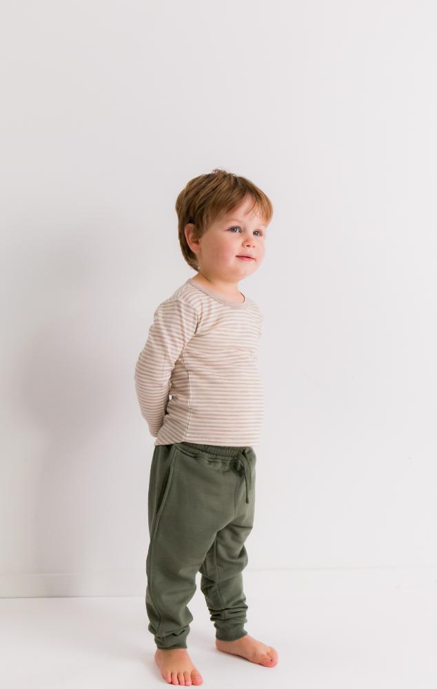 Child wearing a merino striped shirt and green pants against a white background