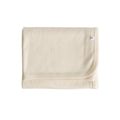 Cream deluxe rib merino swaddle blanket with a brand logo on a white background