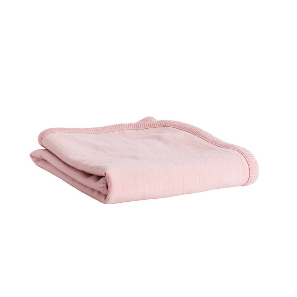 A folded light pink merino fleece/tencel blanket with a ribbed border, shown on a plain white background