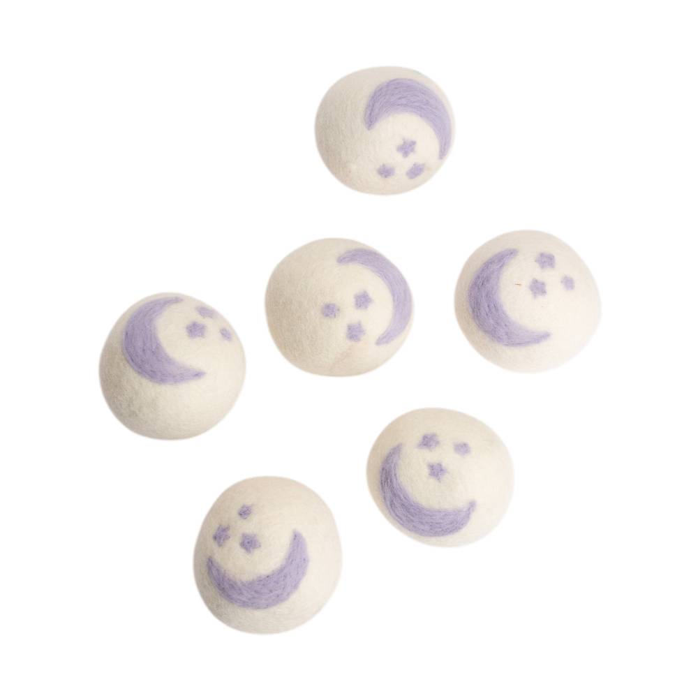 Six cream coloured woolen dryer balls il purple star and moon pattern against a white background