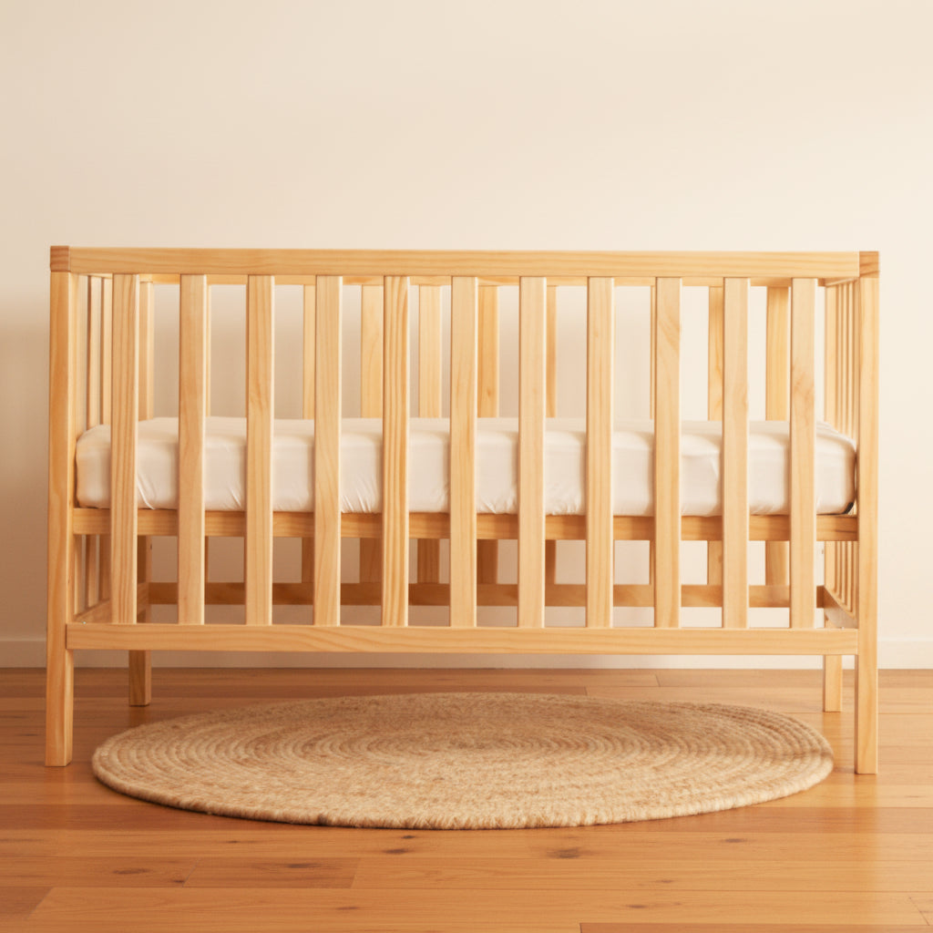 Frank model light pine wood cot on wood floor with natural wool rug