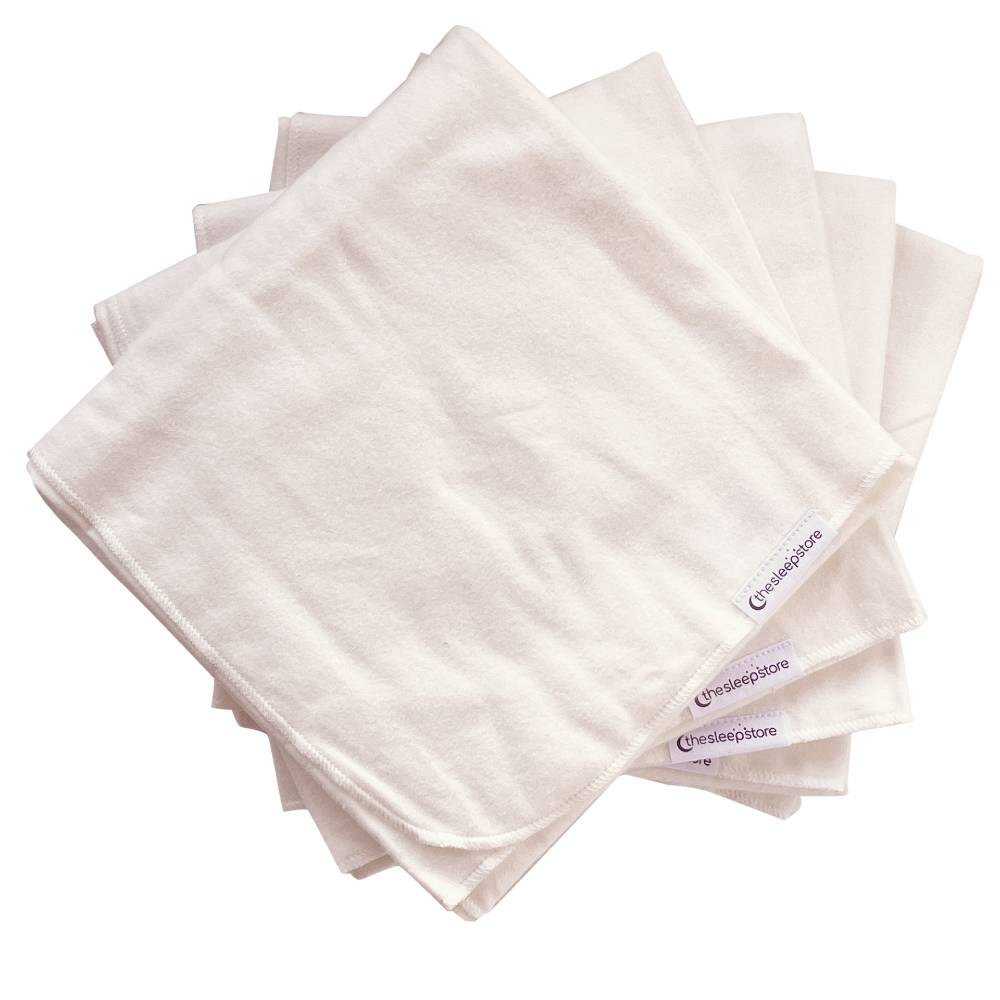 Stack of white cloth nappies with The Sleep Store brand label on a white background