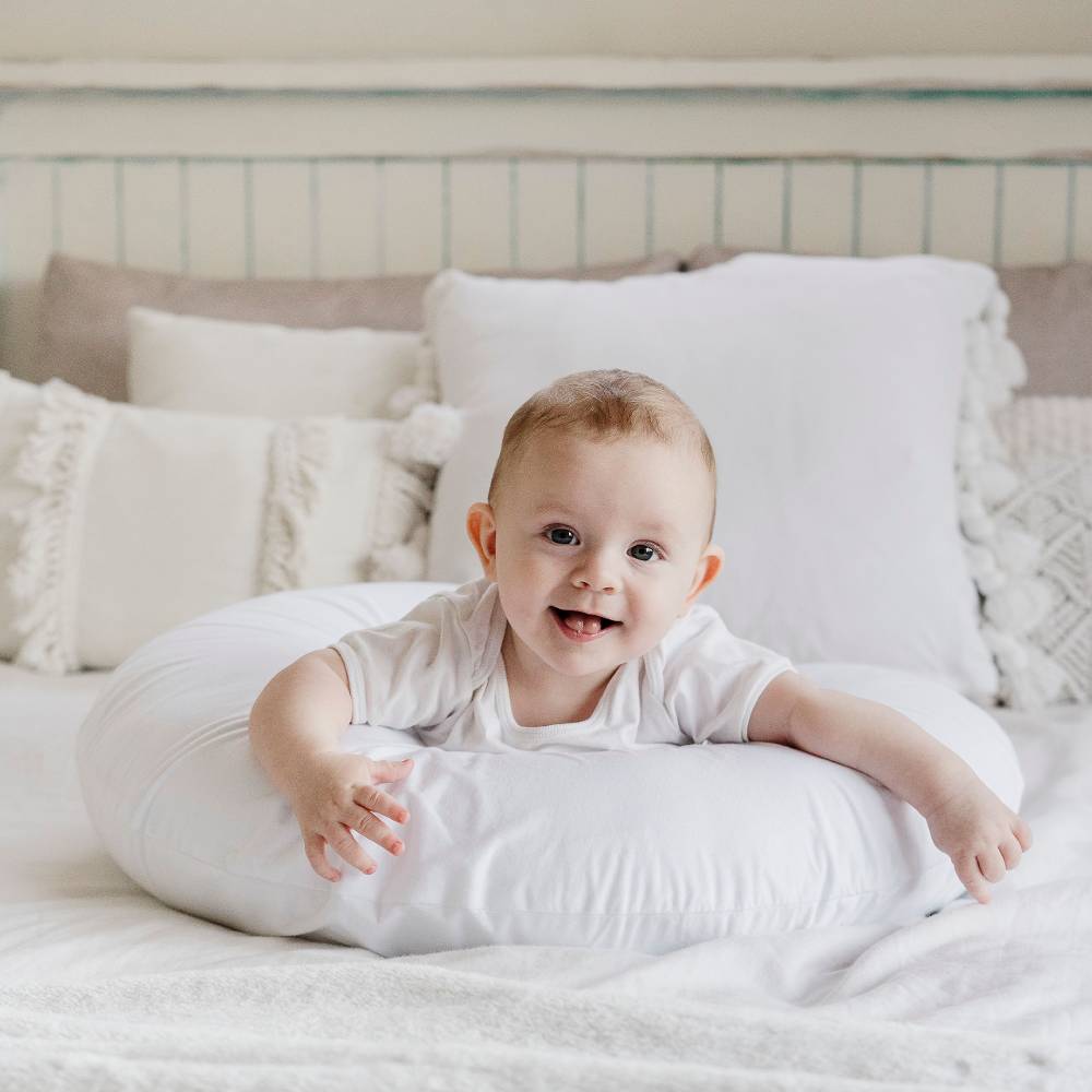 Baby lying on a white pillow in a cozy bedroom setting
