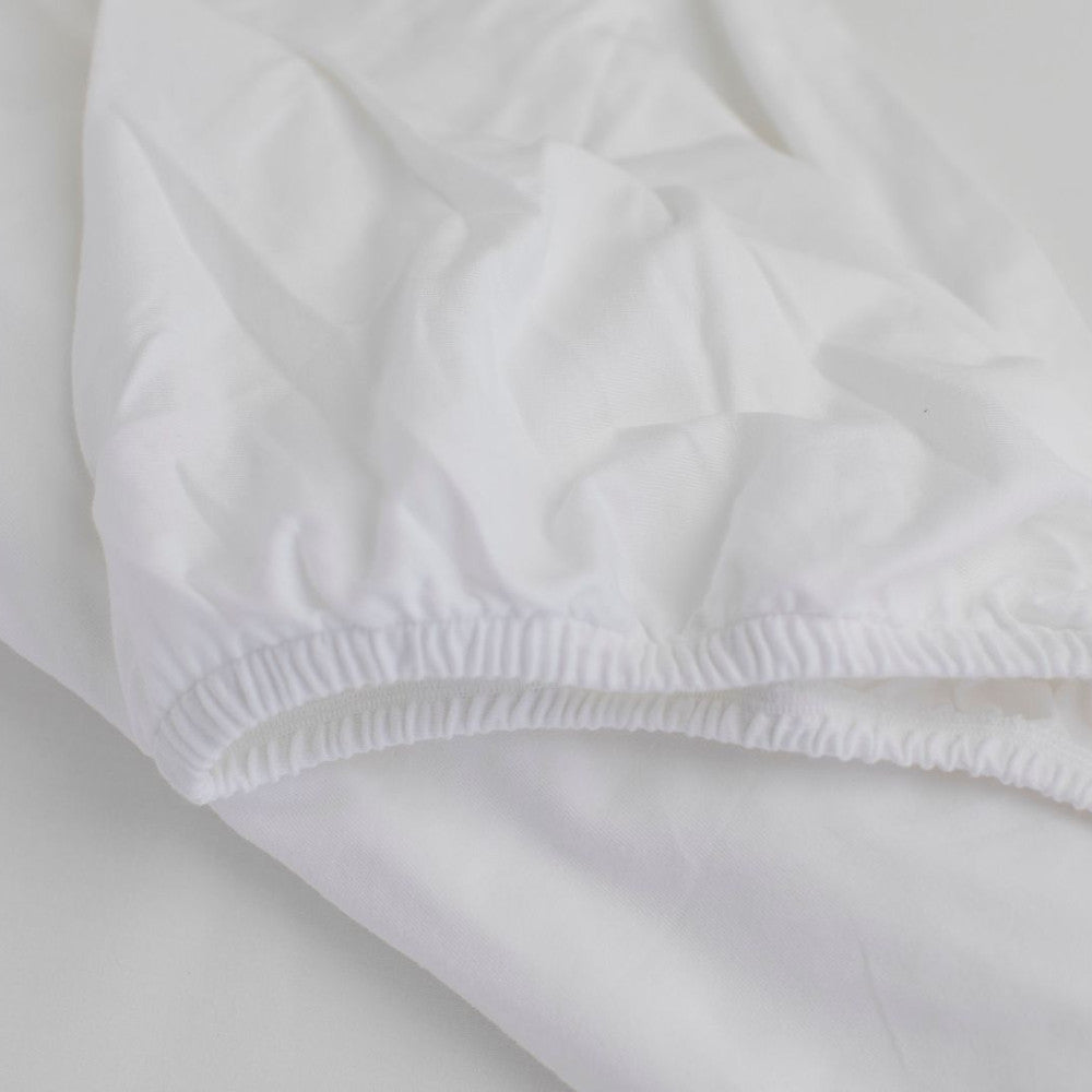 Close-up of white  organic sateen fabric showing elasticated edge on a light background