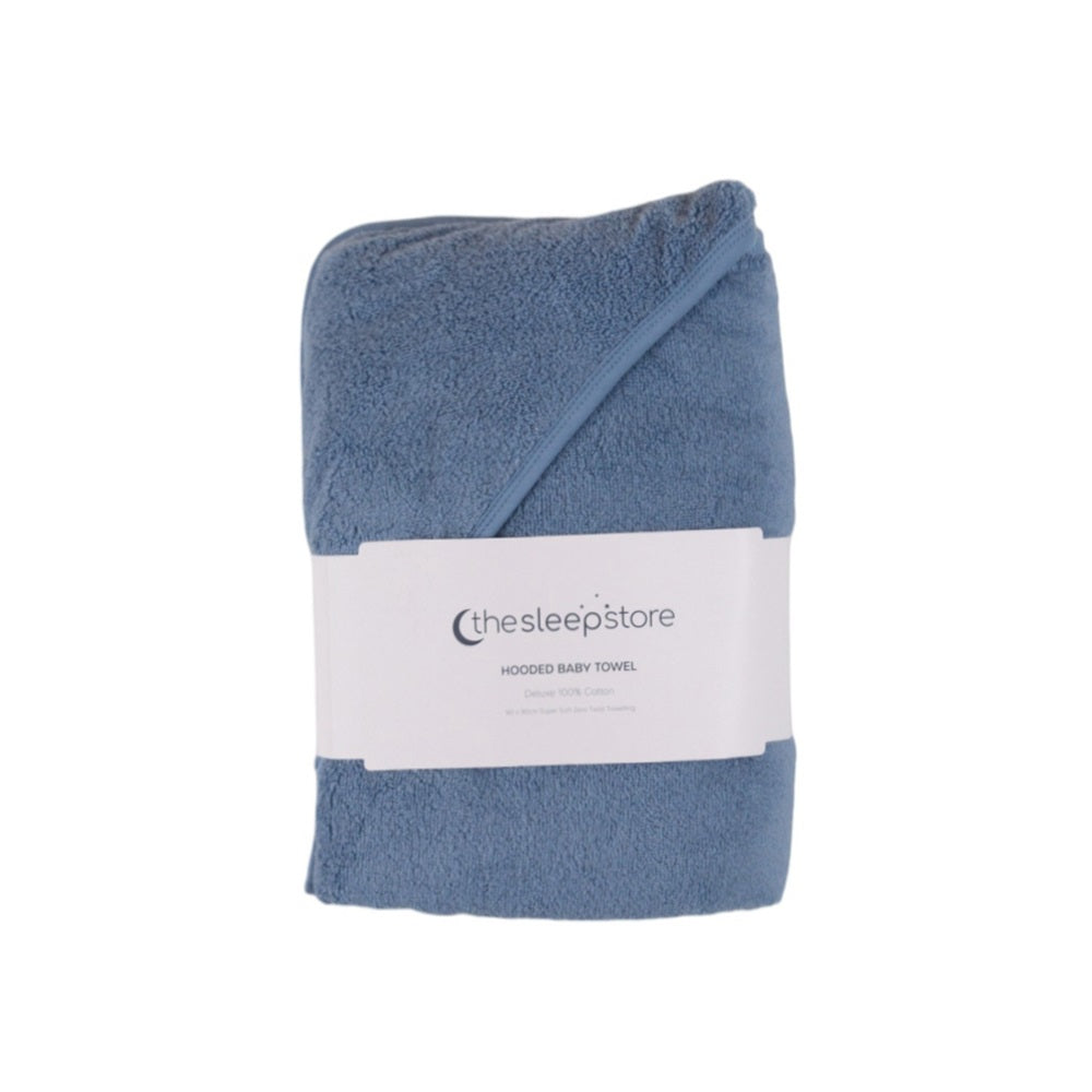 A folded dusty blue hooded cotton terry  baby towel with a white paper label from 'thesleepstore' on a plain white background.