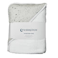 A folded white hooded baby towel with a gray star print on one side, wrapped in a white paper band labeled 'thesleepstore'.