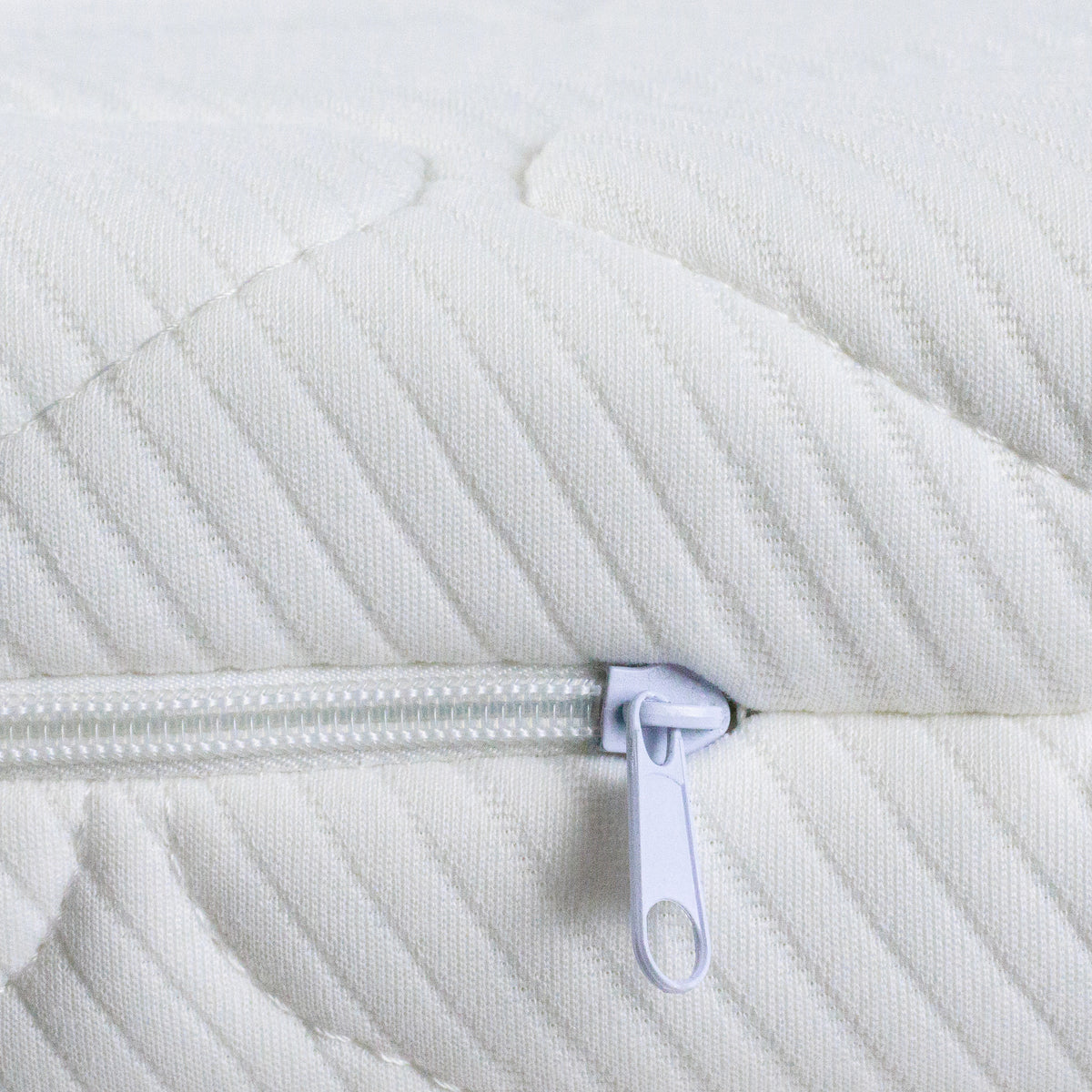 Close-up of a white quilted mattress with  cover and a white zipper 