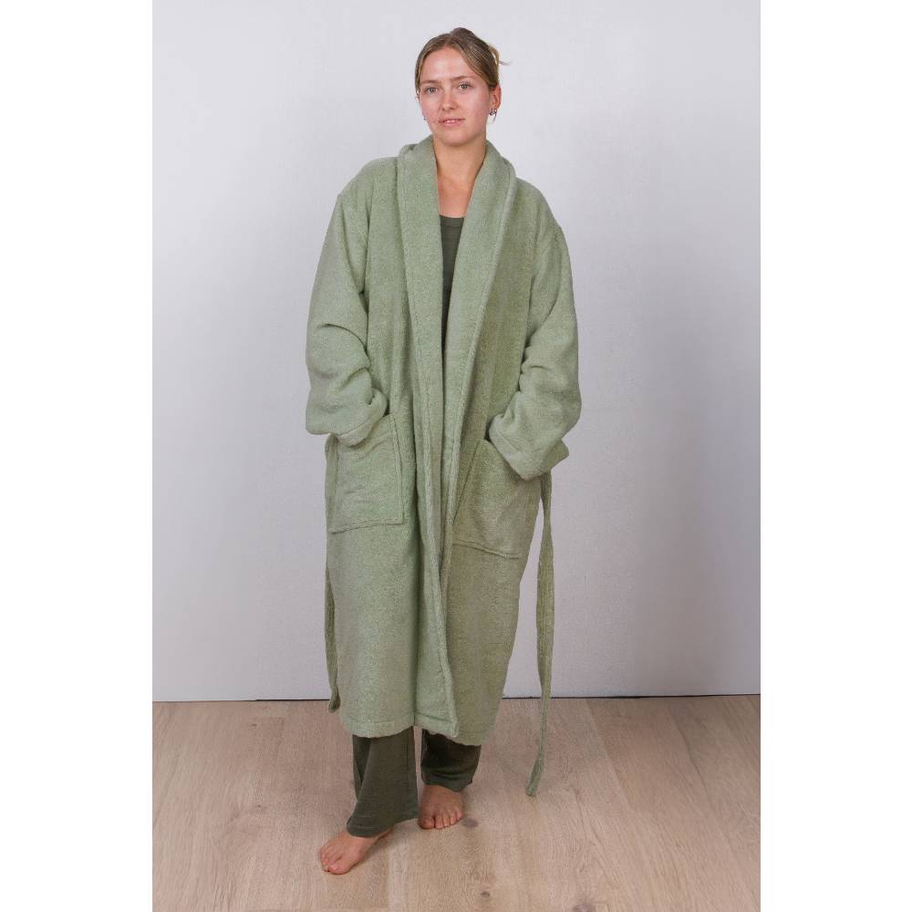 Women wearing a green cotton terry robe standing against a plain background