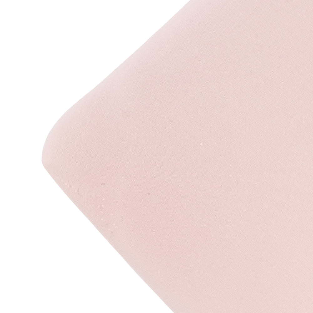 The corner of a mattress with a blush pink colour fitted sheet, on a white background. 
