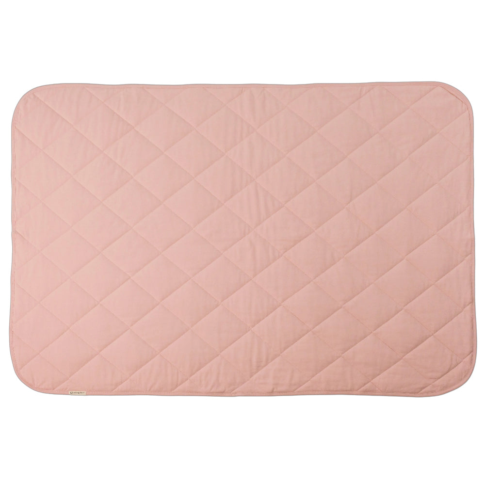 A blush pink colour quilted blanket on a white background. 