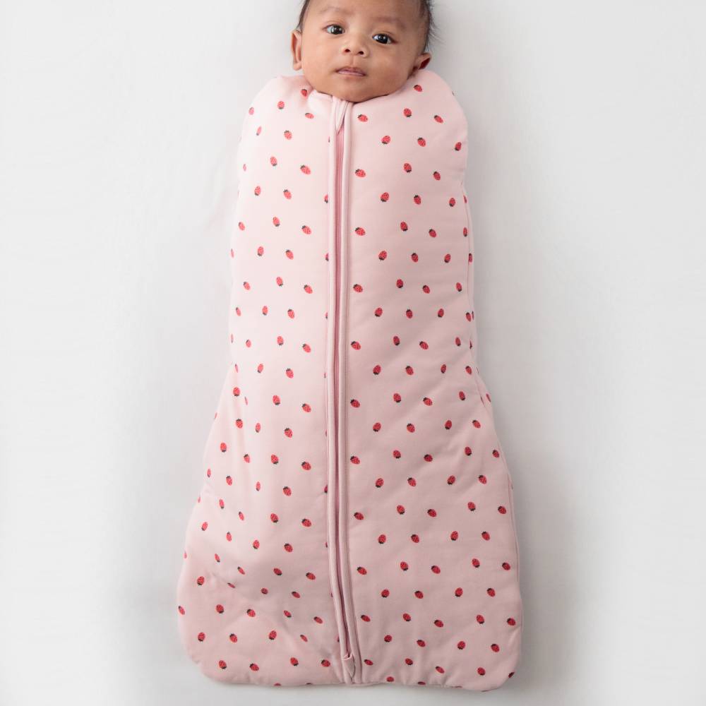Baby wrapped in a pink swaddle with red strawberries on a white background