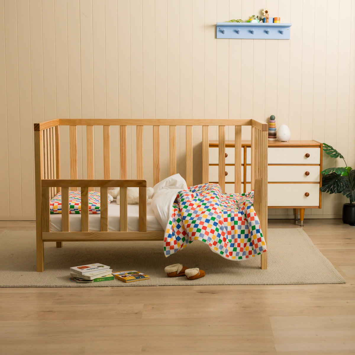 Nursery setting with a cot featuring a check duvet cover. 