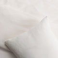 Close-up of a white or cream pillow and a light cream duvet cover 