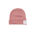 Pink merino baby beanie with a white label on a white background