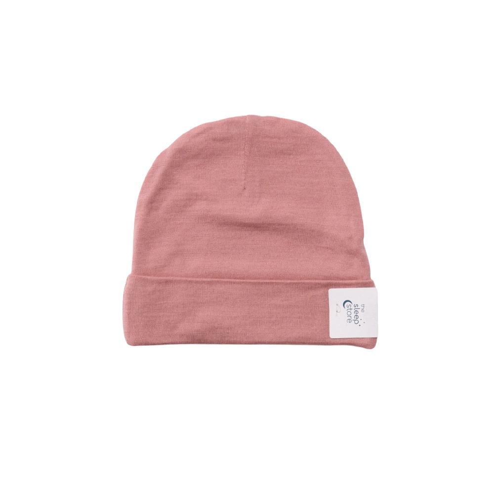 Pink merino baby beanie with a white label on a white background
