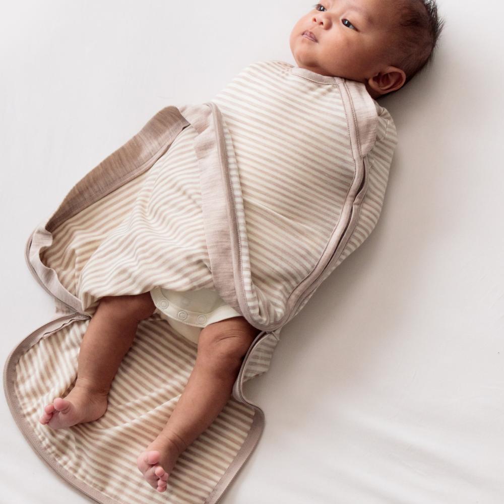 Baby wrapped in a beige swaddle on a white background