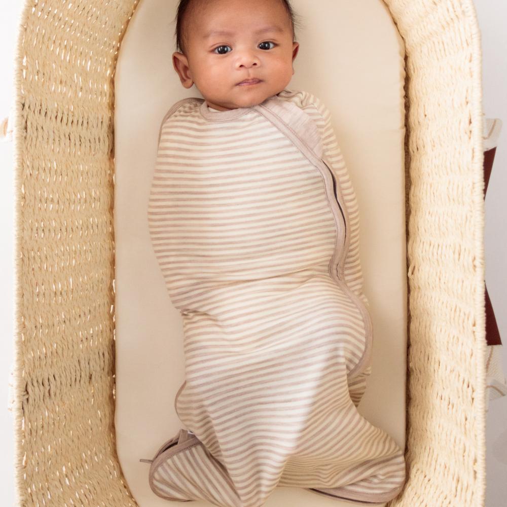 Baby swaddled in a striped blanket lying in a woven basket
