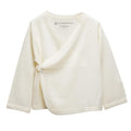 An off-white long-sleeve baby kimono cardigan wrap with a V-neck and snap closure, shown on a plain white background. The brand 'the sleep store' is printed inside the collar.