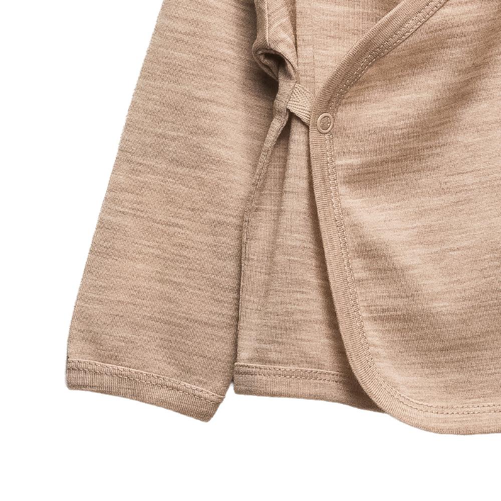 Close-up of a baby kimono wrap cardigan  in a warm sandy beige color, showing the textured fabric, ribbed cuffs, and button closure on a plain white background.