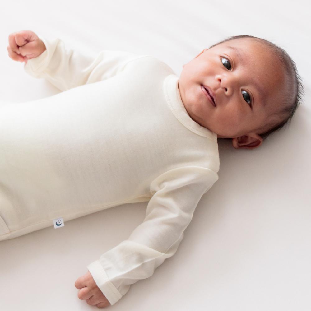 Newborn baby wearing a white long-sleeve bodysuit on a white background