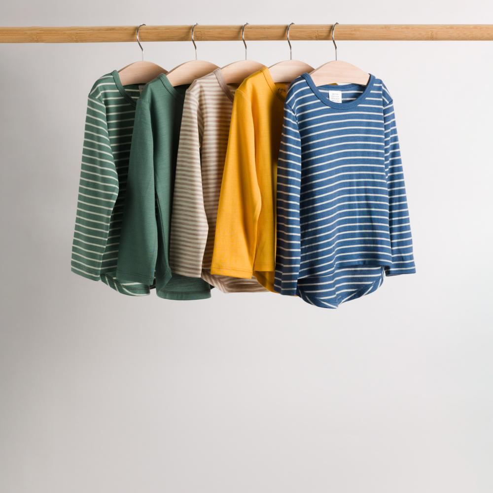 Four merino long sleeve children's tops hanging on a rod