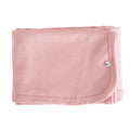 Folded pink merino baby blanket with a small logo on a white background