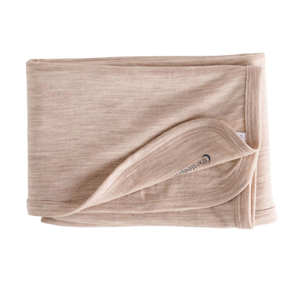 Folded beige merino baby blanket with a brand logo on a white background