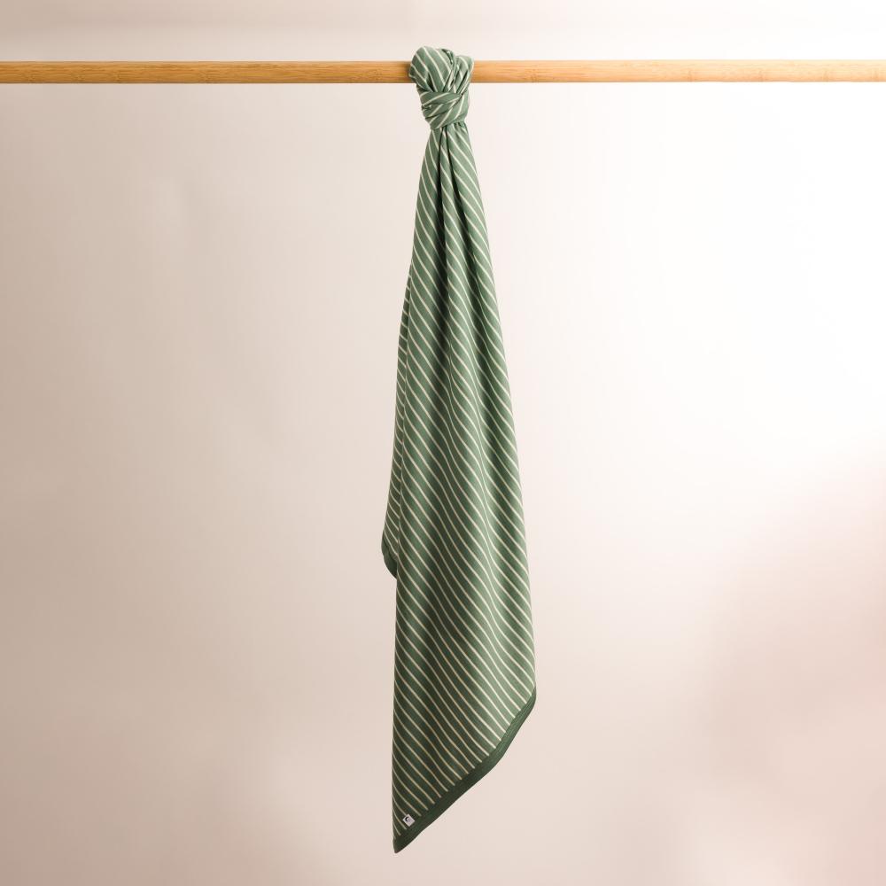 Merino striped towel swaddle blanket on a wooden rod against a beige background