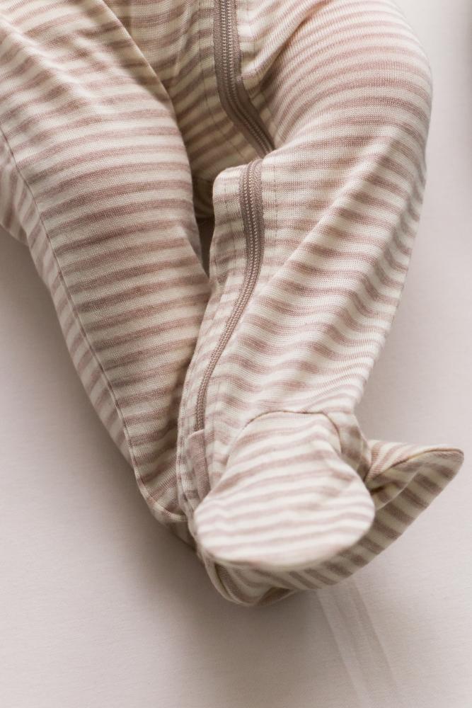 Striped merino baby  footed onesie on a light background