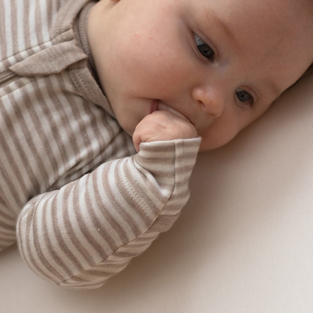 Baby in striped merino onesie with a neutral background