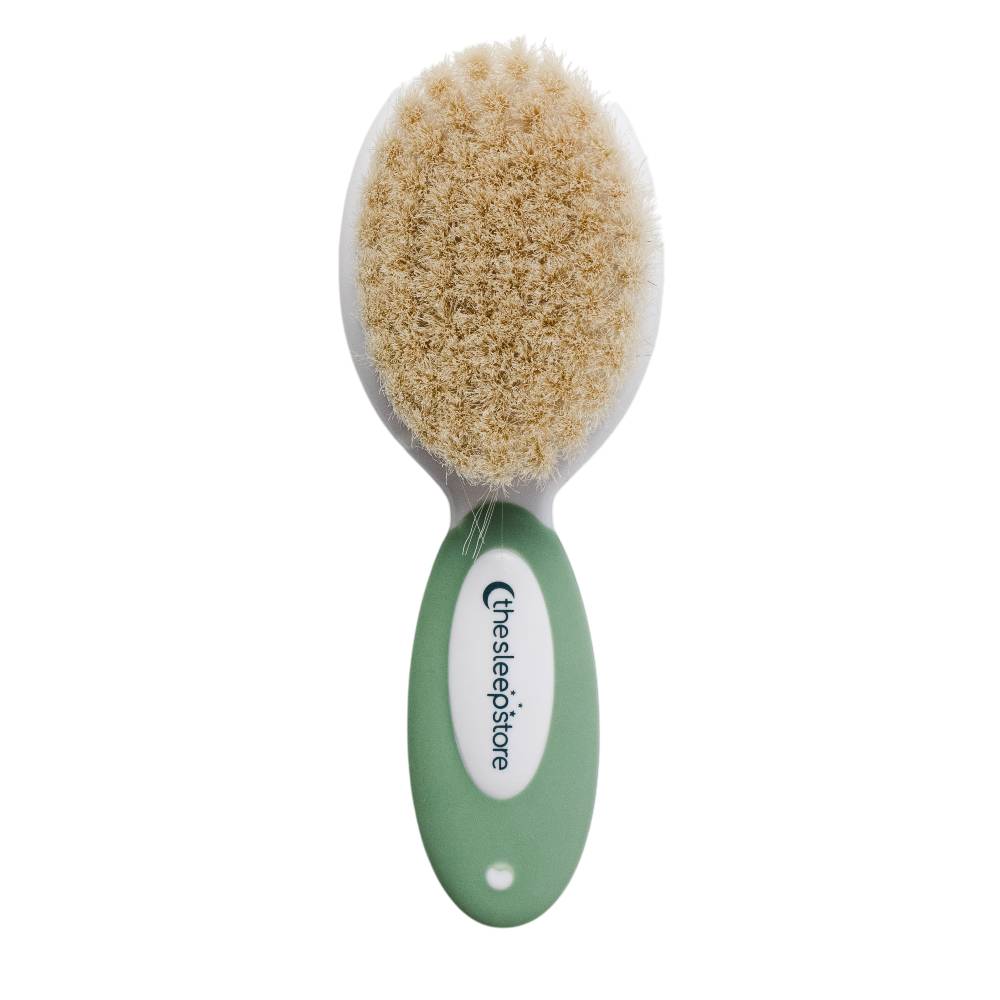 The sleep store green baby brush with beige bristles on a white background