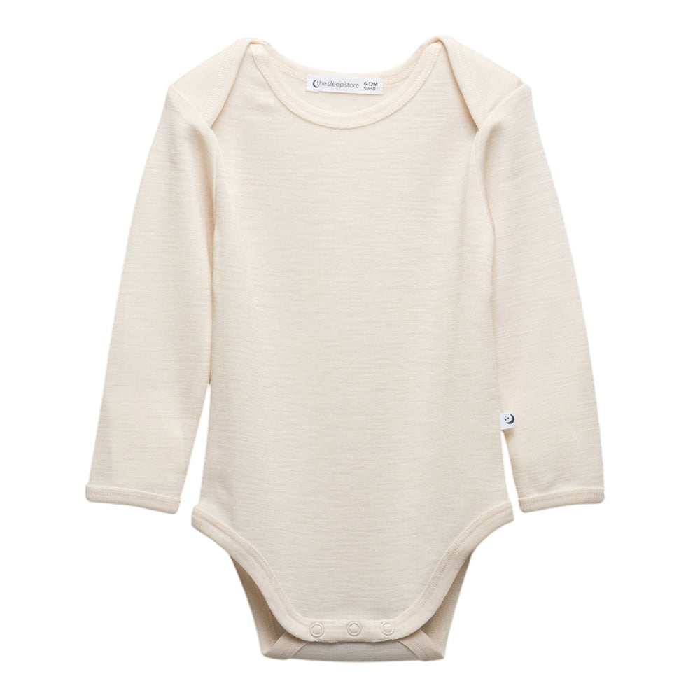 A long-sleeve deluxe merino rib cream-colored baby bodysuit with three snap buttons at the crotch, displayed flat against a solid white background.