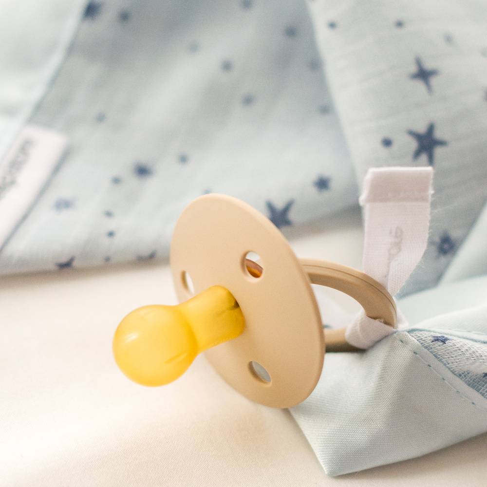 Pacifier attached to cotton muslin comforter