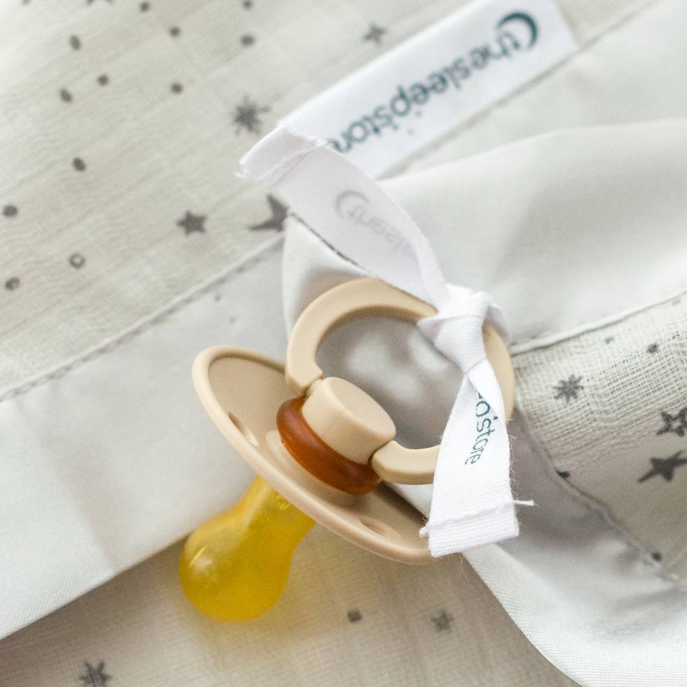 Pacifier attached to cotton muslin comforter
