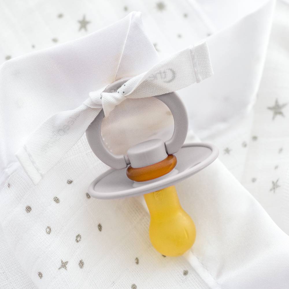 Pacifier attached the cotton muslin comforter.