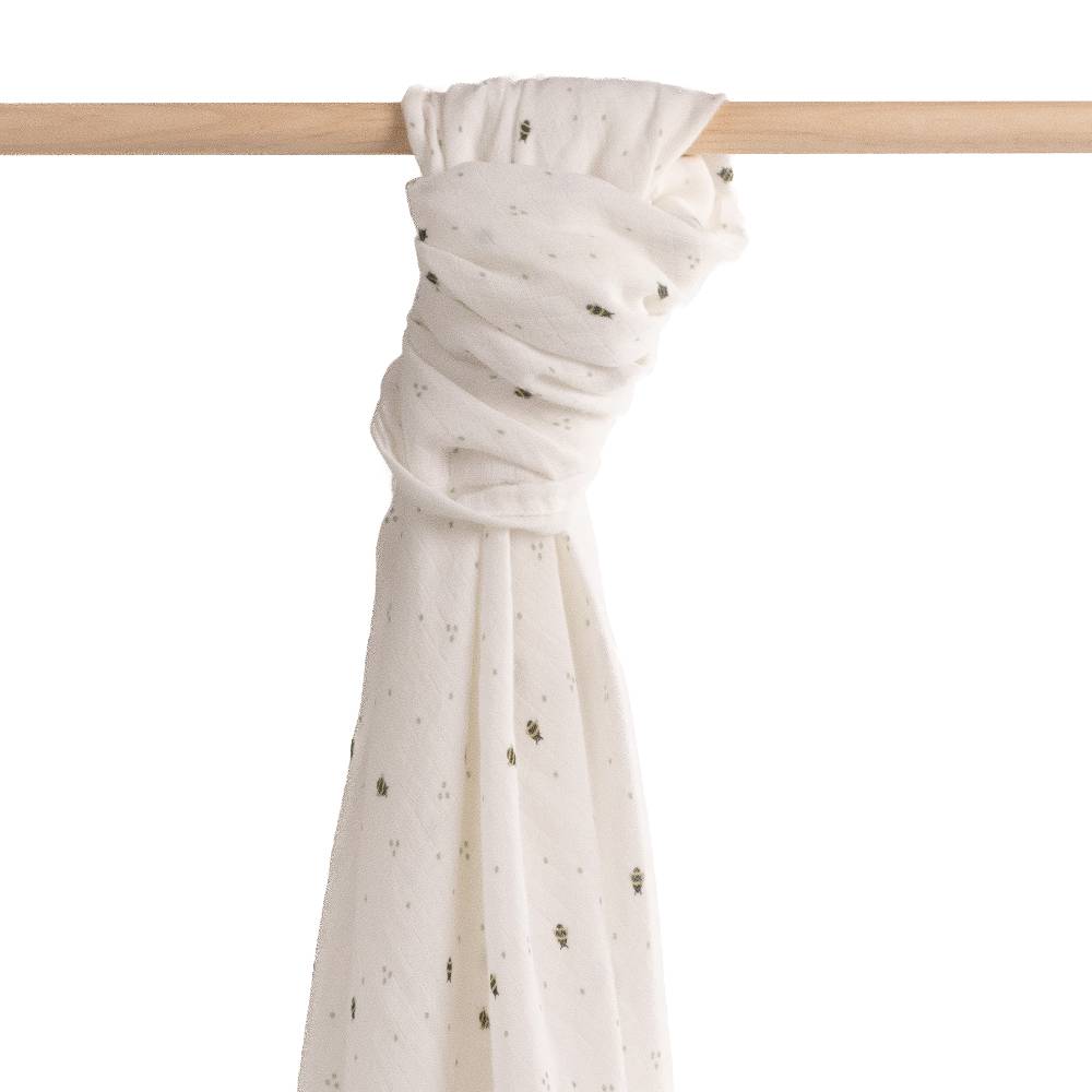  muslin wrap that is white with bee print tied on a  wooden rail;