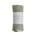 Green muslin swaddle blanket with a label on a white background