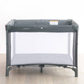Gray baby travel cot on a wooden floor with a white background