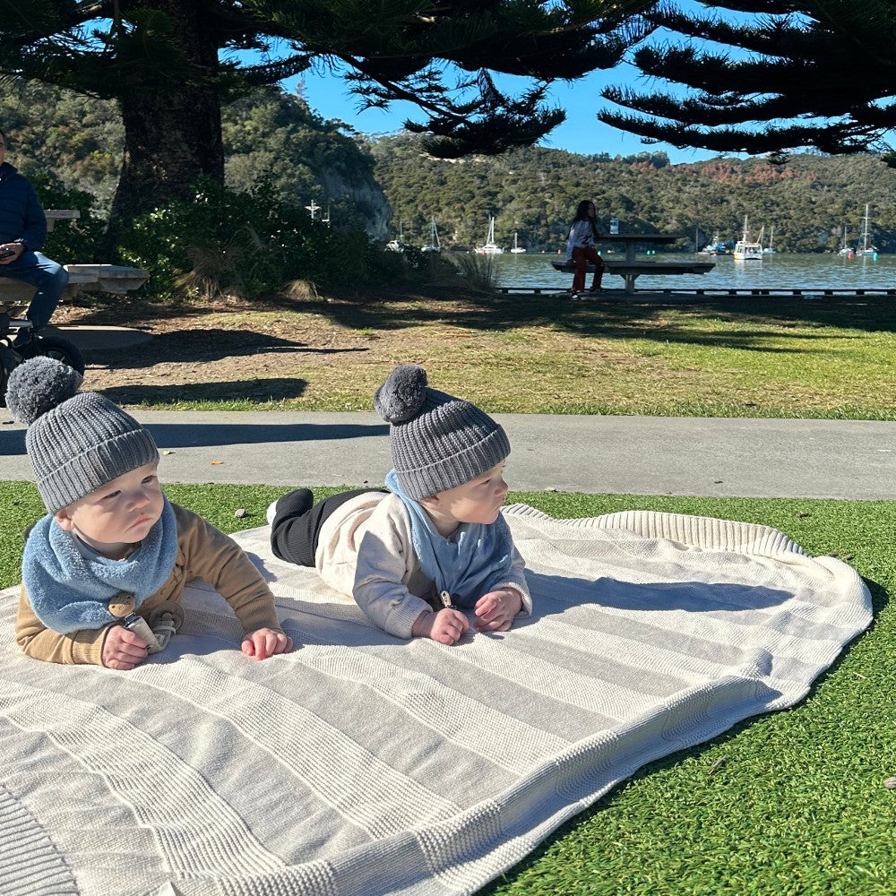 Two children lying on a blanket outdoors with a scenic background