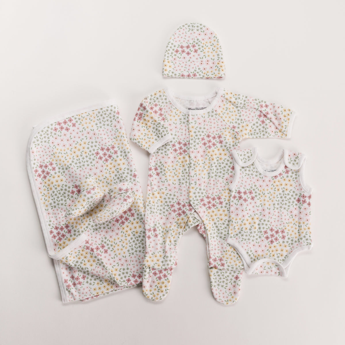 Floral gift pack with onesie, singletsuit booties, beanie and swaddle on white background