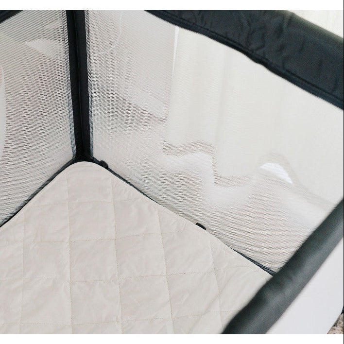 Quilted wool topper in a mesh travel cot