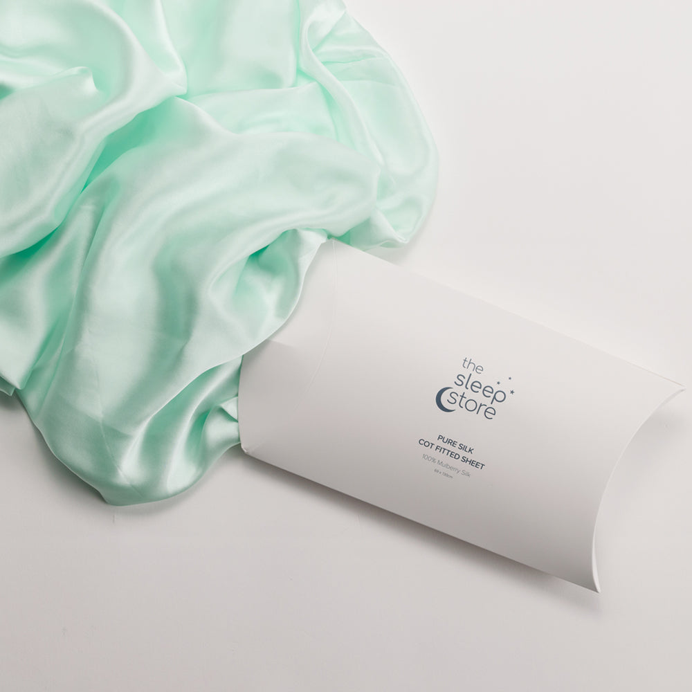 Mint green satin sheet with 'The Sleep Store' packaging on a light gray background