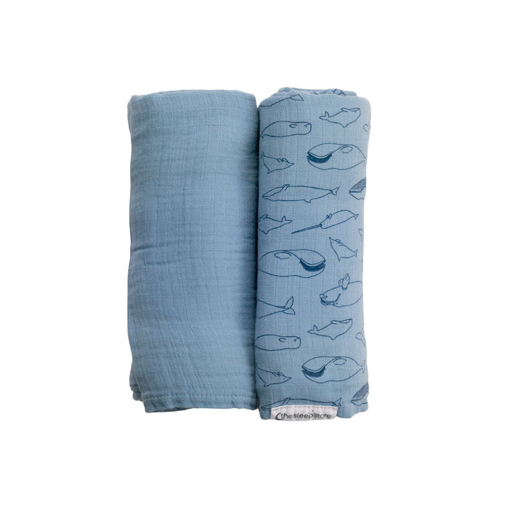 Two blue swaddle blankets, one plain and one with whale pattern, on a white background.