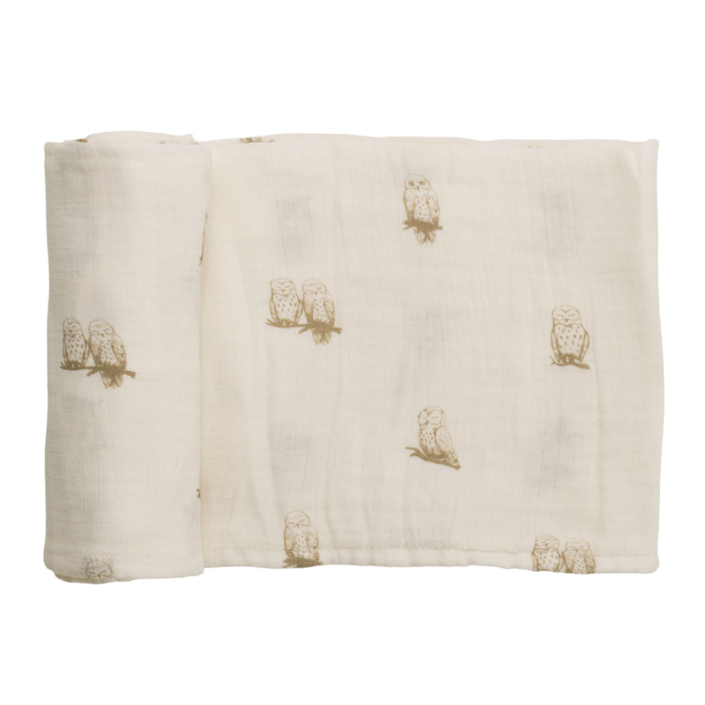 Cream coloured baby muslin swaddling wrap with owl patterns on a white background