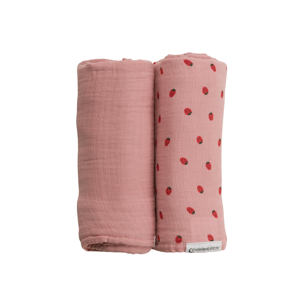 Two pink swaddle blankets, one plain and one with strawberry pattern, on a white background.