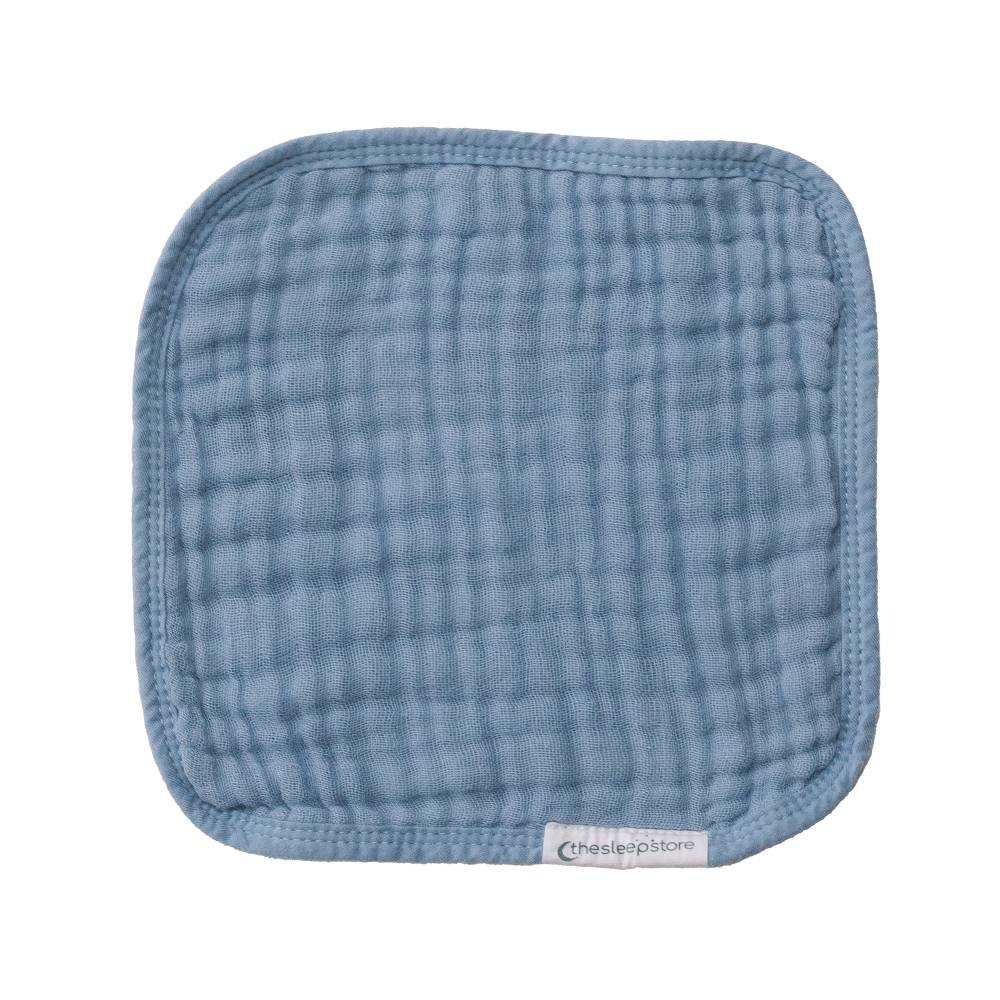 Blue muslin face cloth with brand label on a white background
