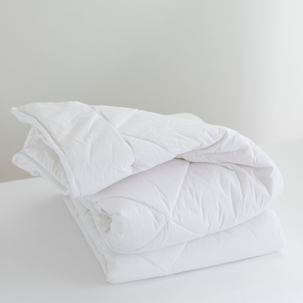 White comforter on a bed with a light gray background