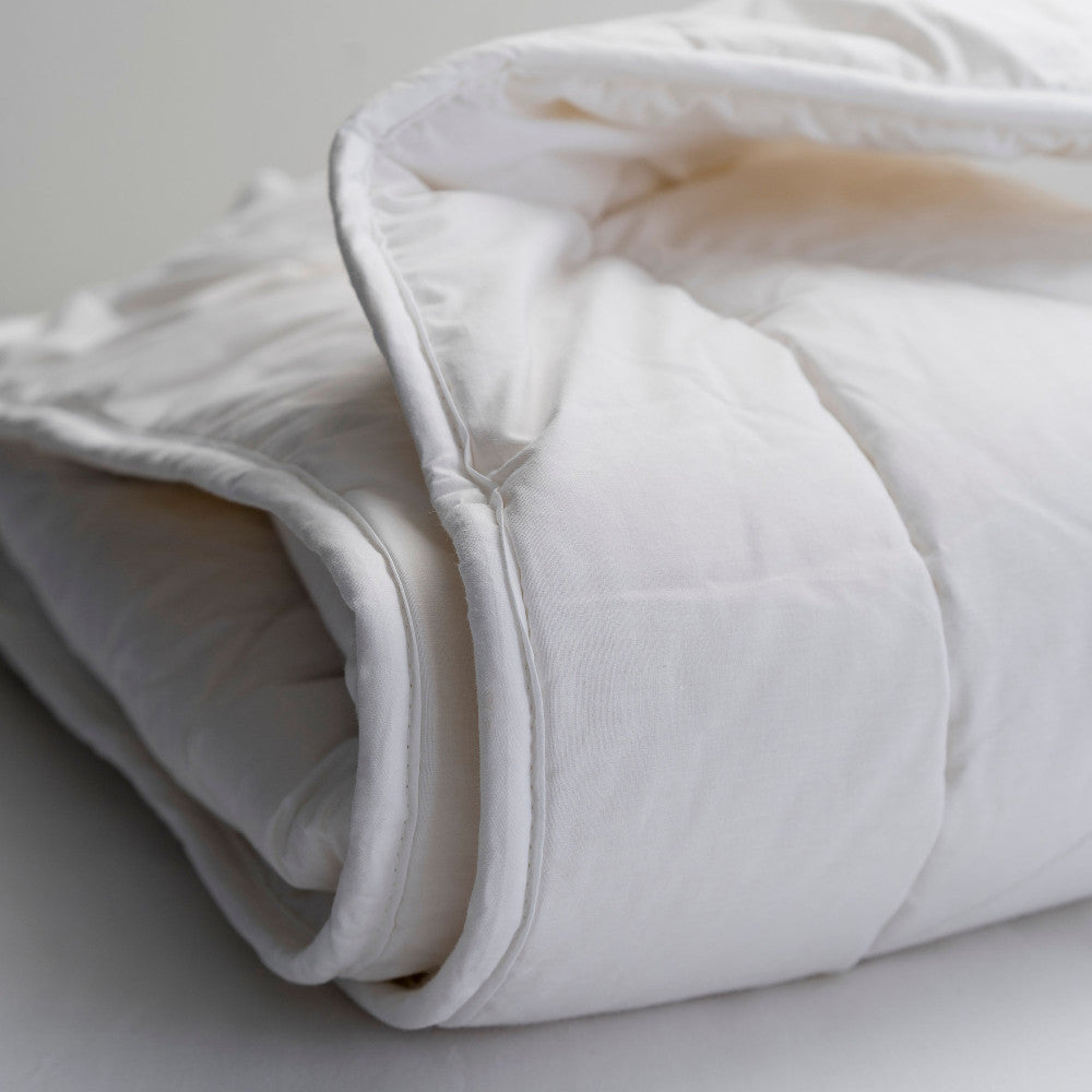Folded white comforter on a light gray background