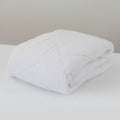 Folded white comforter on a bed with a neutral background
