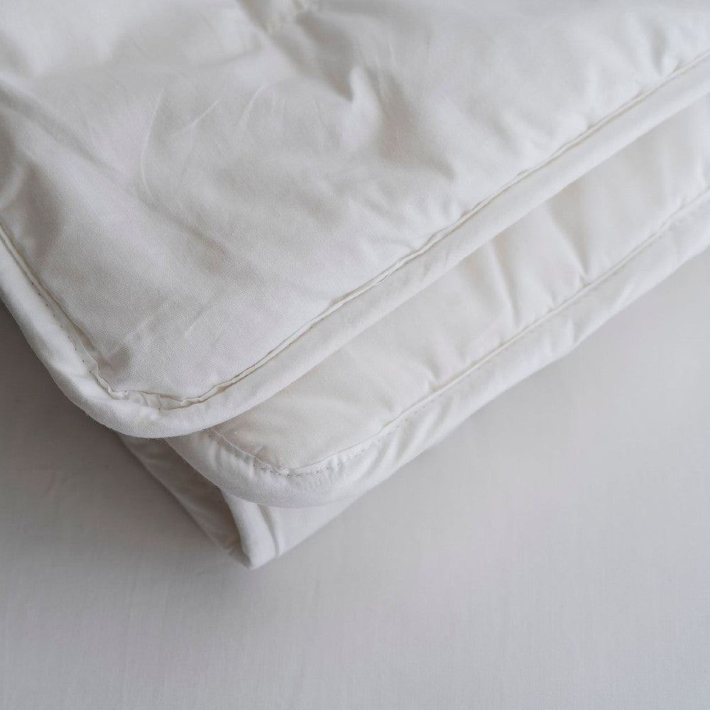 Close-up of a white wool comforter on a light gray background